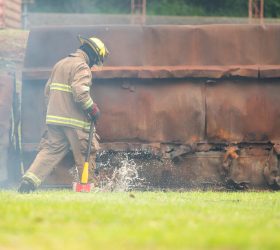A firefighter run through Water mist and heavy smoke holding a rescue axe during an emergency response drill