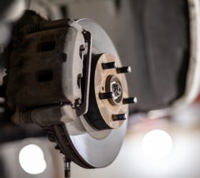 Disc brake of the vehicle for repair, in process of new tire replacement. Car brake repairing in garage.Suspension of car for maintenance brakes and shock absorber systems. Replacement of brake pads.
