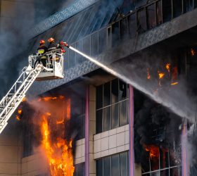 A closeup of Firefighters on the stairs extinguish a big fire