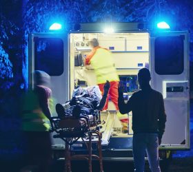 Doctor and paramedic of emergency medical service take care of old ill man. Team of emergency medical service rescuing old patient. Concepts health care, rescue and goodbye.